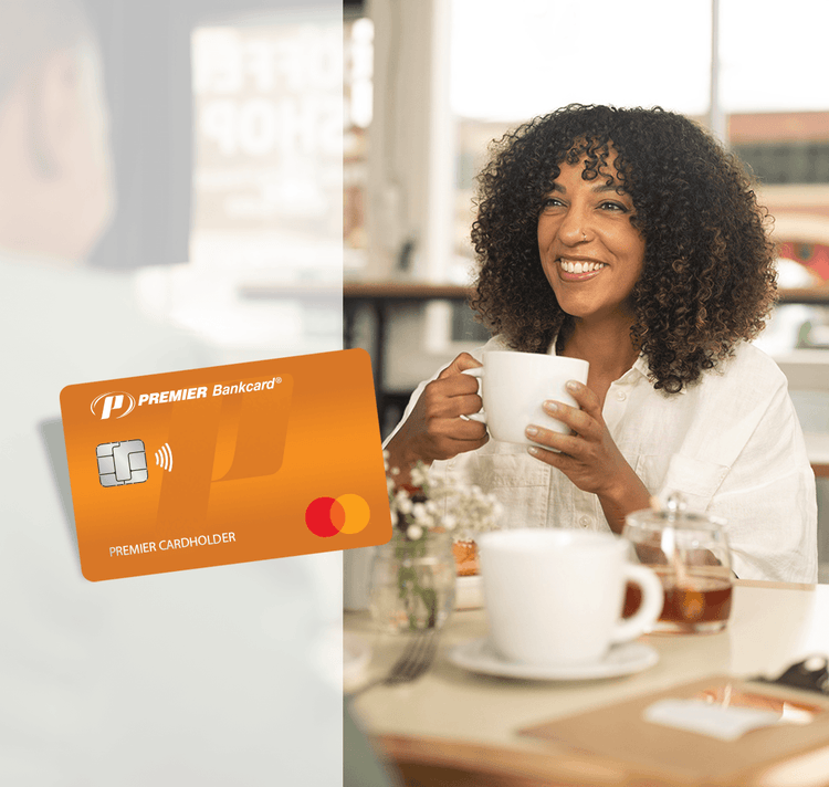 woman sitting at table, holding a mug; to the left of the woman is an overlay image of an orange PREMIER Bankcard Mastercard